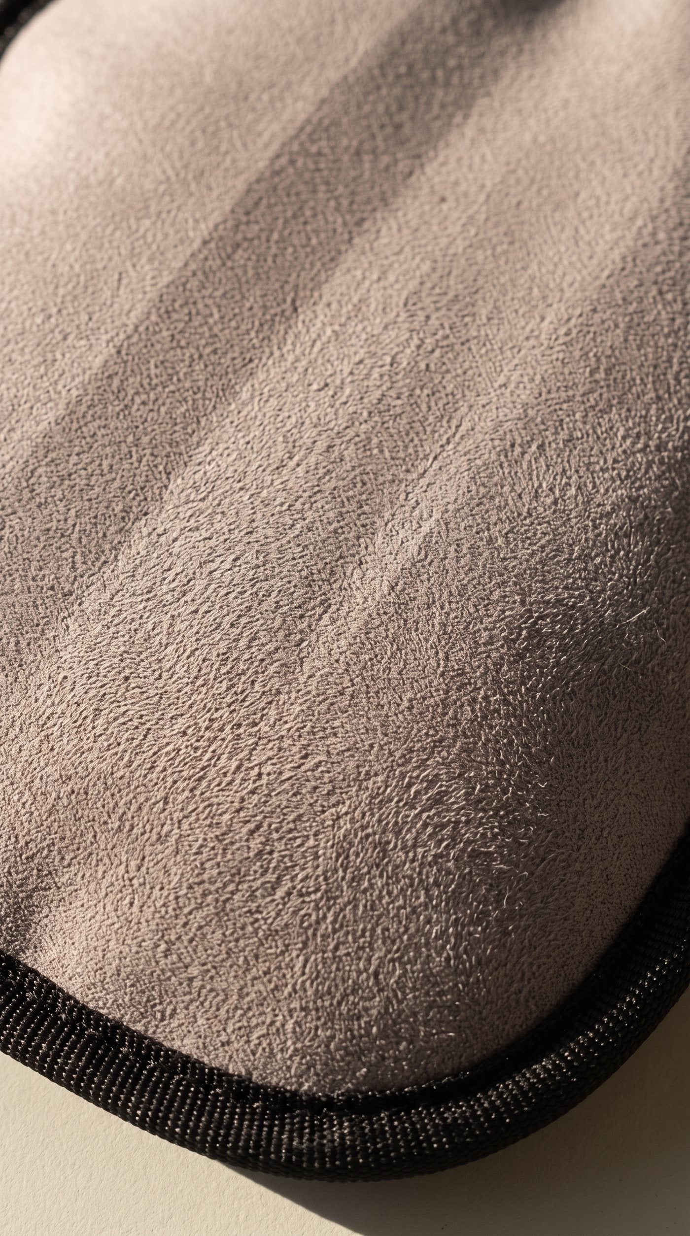 Macro de la face active : un velours ras gris-taupe, plat et mat, en lumière rasante