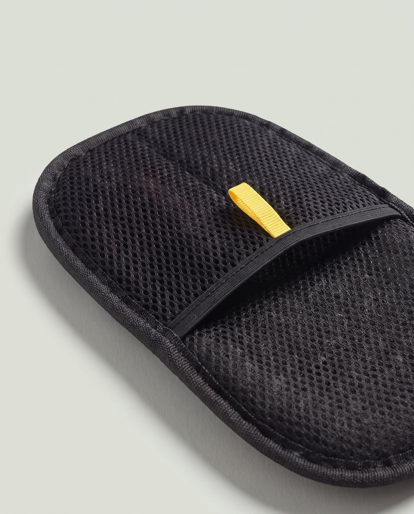 Macro du dos du gant : maille noire alvéolée, liseré droit fermant la poche, passant jaune